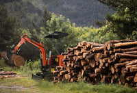 a small excavator removing piles of tree logs